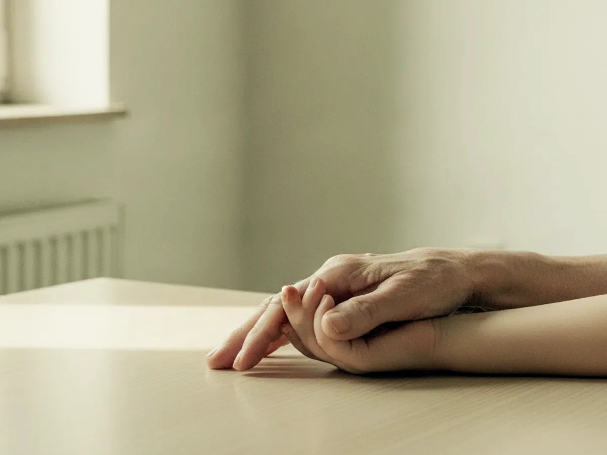 Hand eines älteren Menschen und Hand eines Kindes auf einem Tisch